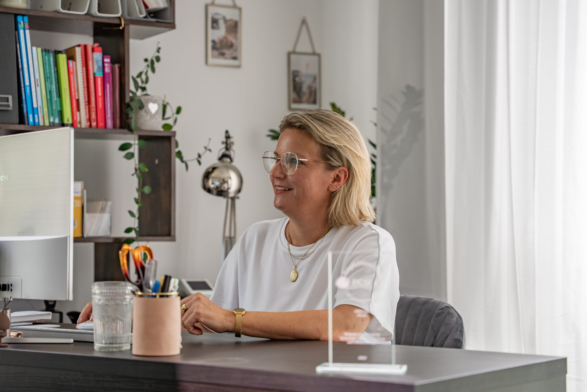 Therapeutin der JUNA GbR Herten am Schreibtisch mit Fachliteratur im Hintergrund — professionelle Praxisverwaltung und Terminvergabe für systemische Therapie und Beratung in Herten