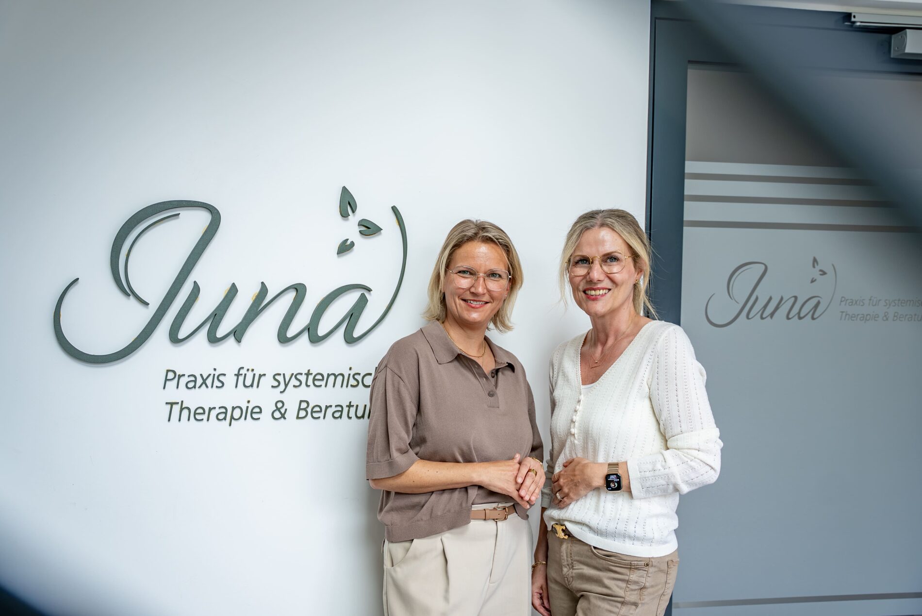 Die Gründerinnen der JUNA GbR, Julia Spoden und Nadine Frischmann, vor dem Praxislogo in Herten — DGSF-zertifizierte systemische Therapeutinnen und Beraterinnen